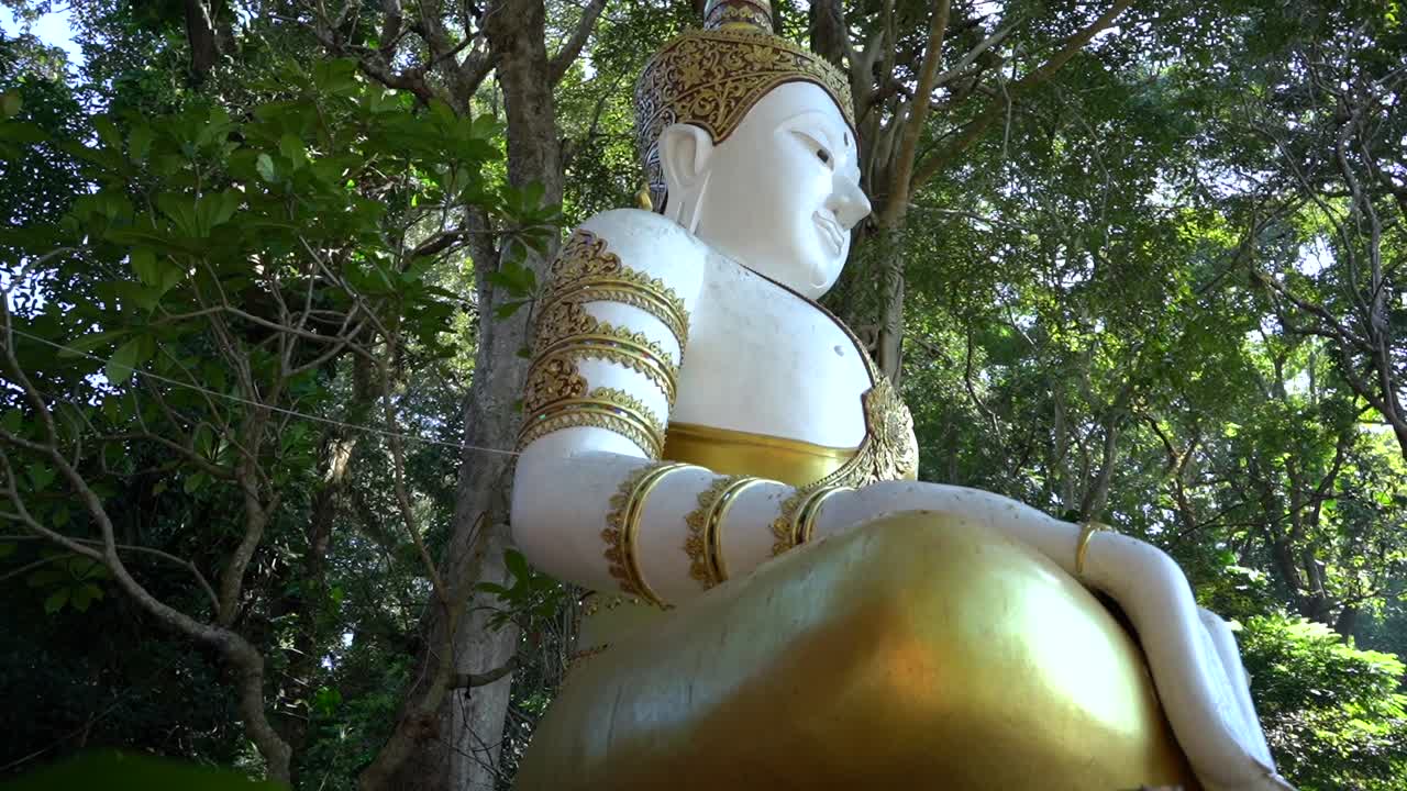 Serene White and Gold Buddha Statue in Lush Green Forest