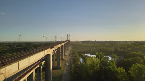 Dolly-in-flying-alongside-Zarate-Brazo-Largo-road-and-railway-complex-cable-stayed-bridge-between-green-fields-at-golden-hour,-Entre-Rios,-Argentina