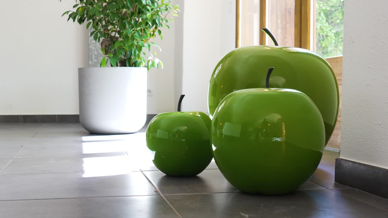 objeto decorativo de manzanas verdes en una sala de estar, con una ventana en el fondo y una planta