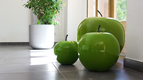 Objeto-Decorativo-De-Manzanas-Verdes-En-Un-Salón,-Con-Una-Ventana-Al-Fondo-Y-Una-Planta.