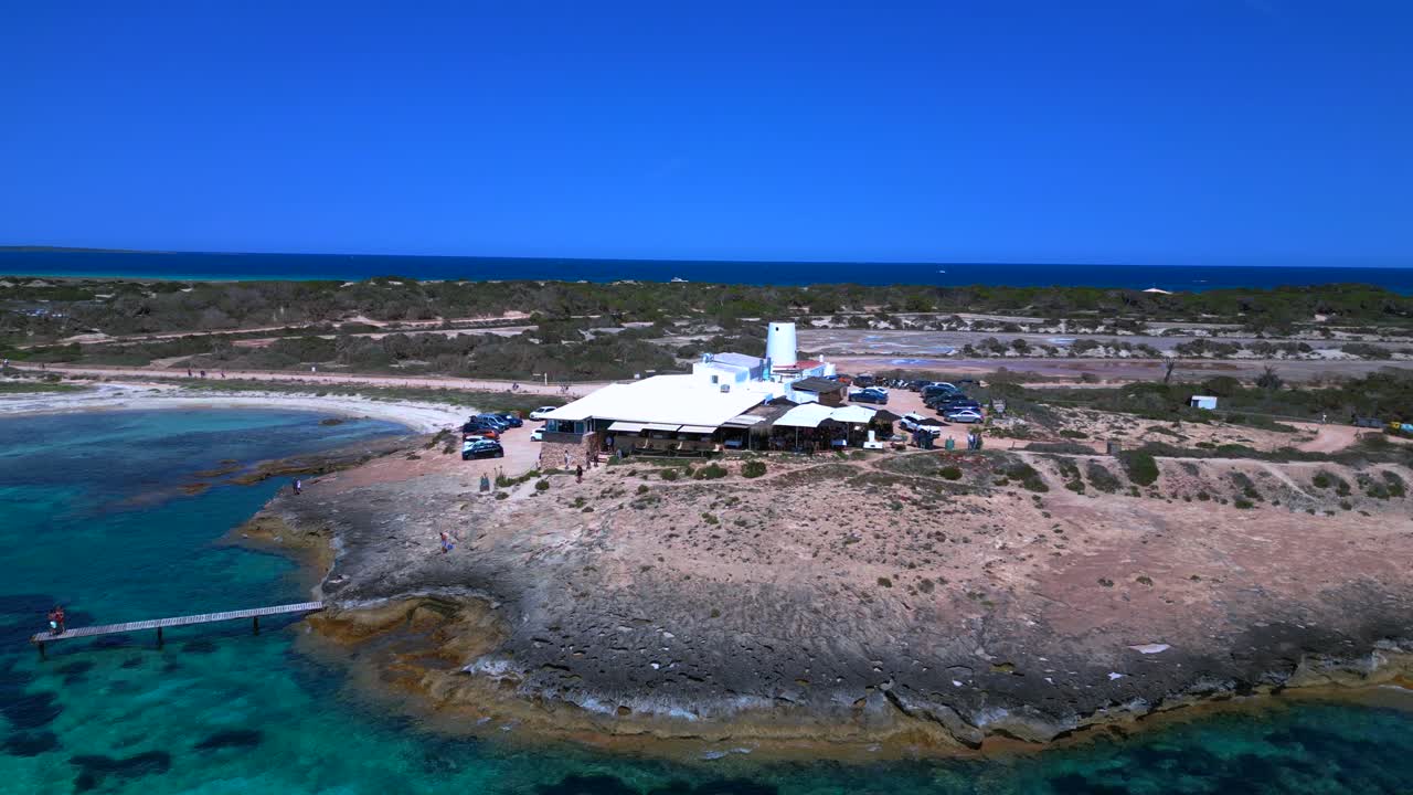 Sailboats anchored in turquoise waters near a beach Restaurant on the idyllic island Formentera, Spain. Best aerial view flight fly push forward drone