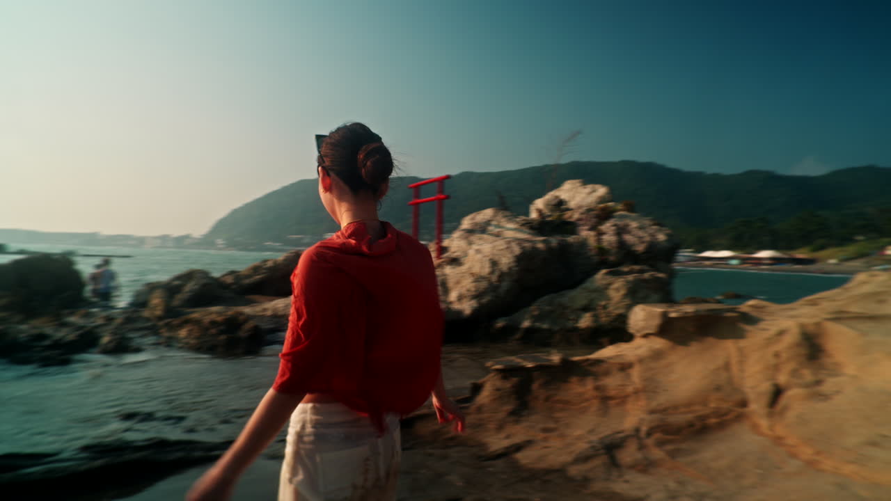 Woman on a rocky beach with a torii gate