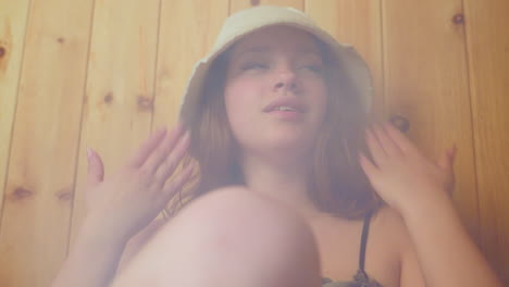 lady sits against wooden wall in steaming sauna, leaning back with eyes closed and relaxed posture while friend partially visible beside her, soft steam swirling around them in warm cozy wellness space