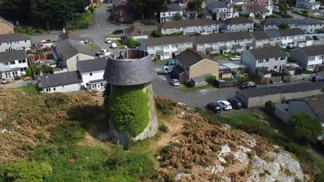 Melin-Wynt-Y-Craig-disused-Llangefni-windmill-ivy-covered-hilltop-Anglesey-landmark,-rising-aerial-view