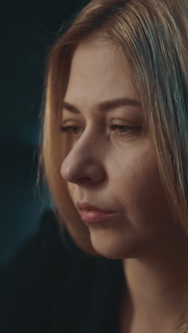 suspecting blonde woman holds pill bottle with prescribed biologically active additives on blurred background in semi-dark room close side view slow motion