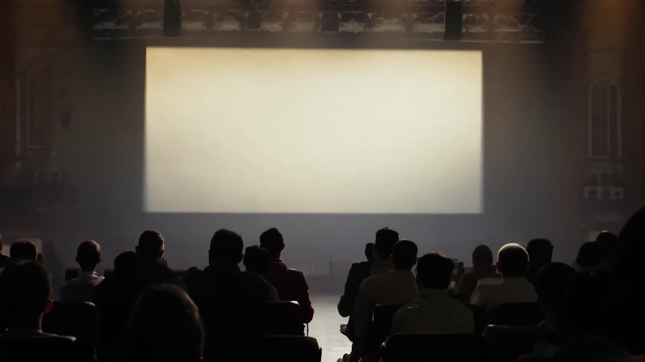 관객들은 극장에 앉아서 밝고 은 화면을 쳐다보며 기대와 호기심의 순간을 만니다.