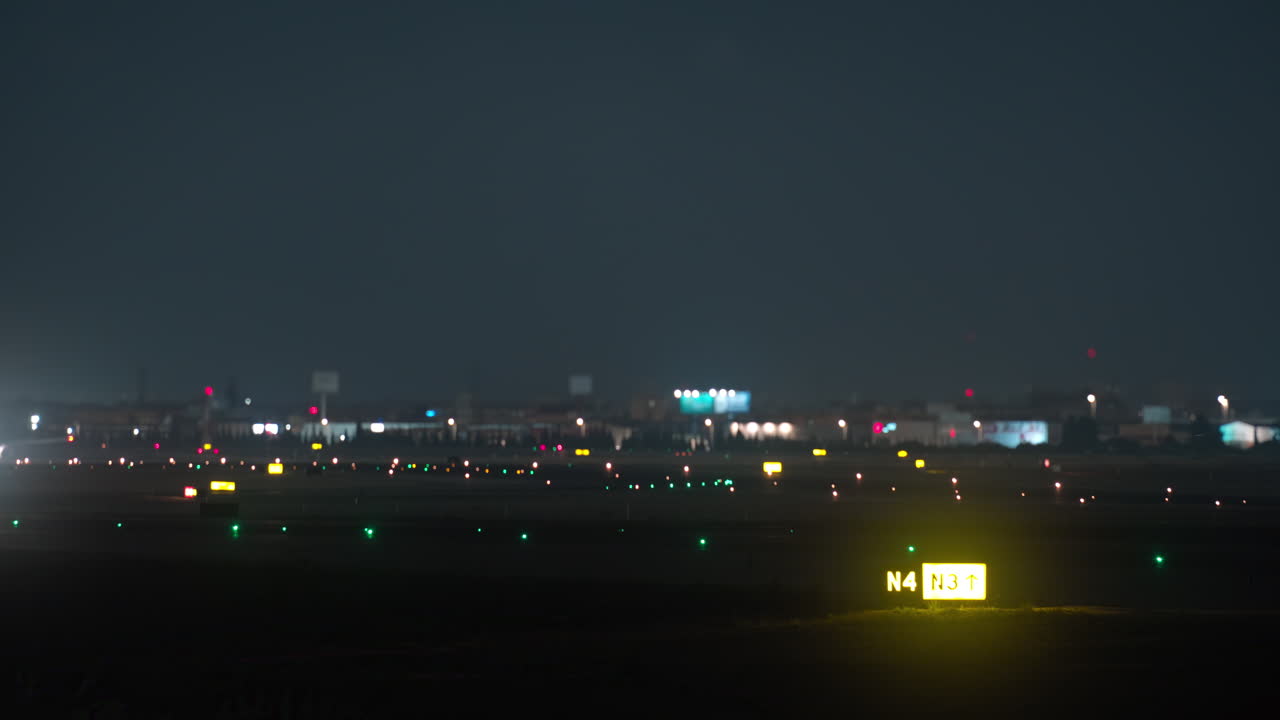 夜、ライトアップされた空港の滑走路を走行する大型飛行機