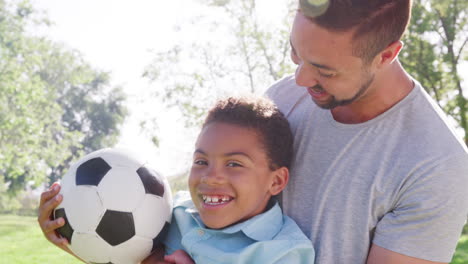 Toma-En-Cámara-Lenta-De-Padre-E-Hijo-Jugando-Juntos-Con-Una-Pelota-De-Fútbol-En-El-Parque