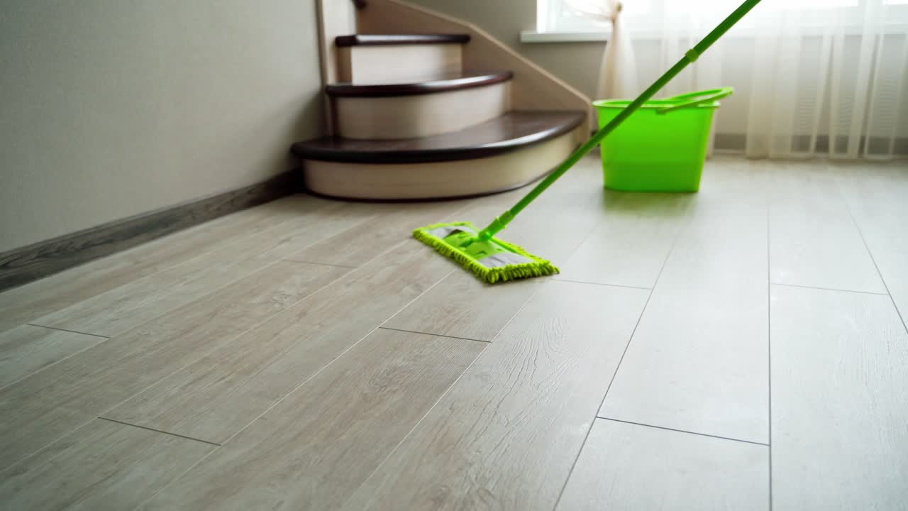 Washing the laminate floor with a mop. Housekeeper with mop and bucket is cleaning floor at home. Floor care concept.
