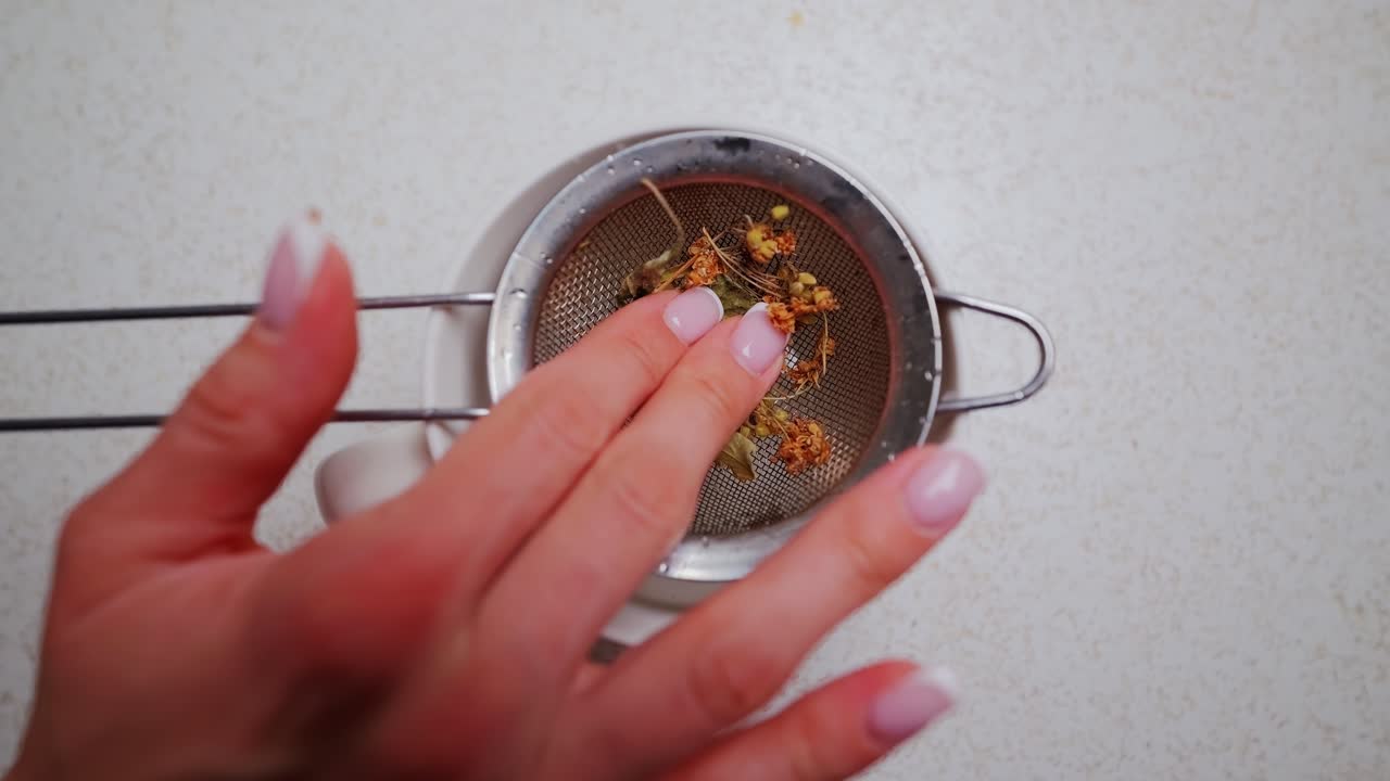 Natural tea ritual in soft motion as leaves settle gently into sieve