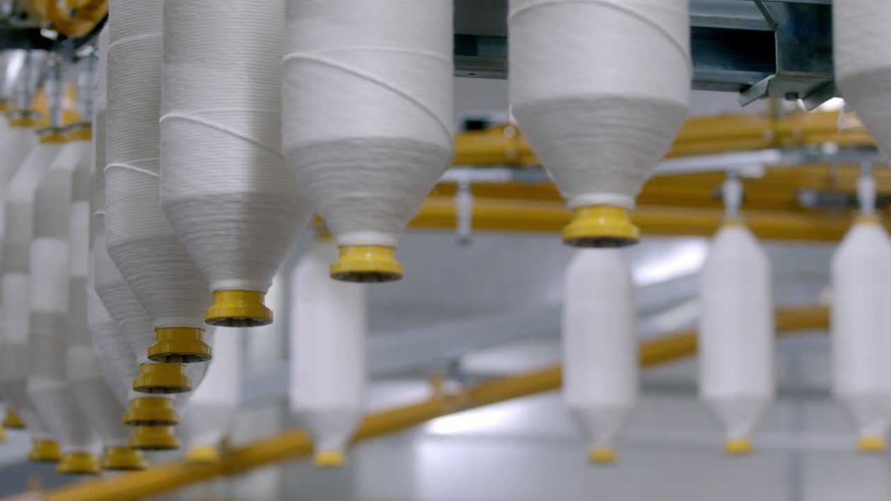 cotton thread yarns spools, textile factory, cinematic shallow focus depth, Organic cotton yarn used for sustainable eco-friendly cotton yarns fabric decentralised production