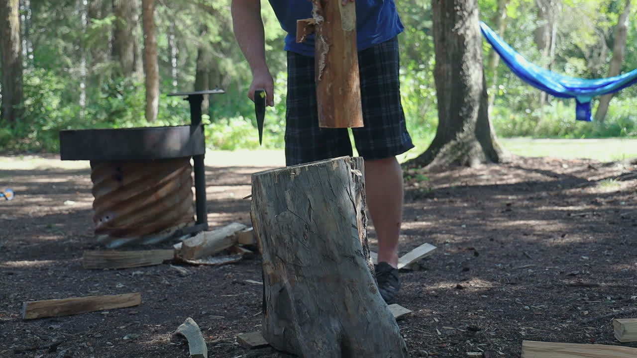 남자는 캠핑장에서 슬로우 모션으로 도끼로 나무를 자른다
