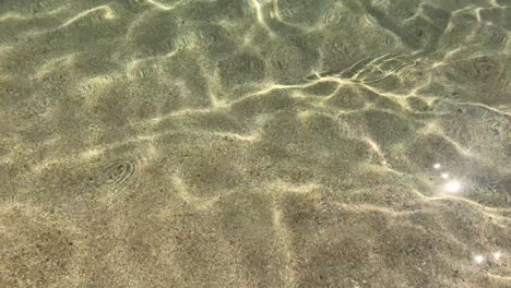 water ripples in crystal clear water with sandy sea floor in 4k