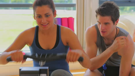 mujer en la máquina de remo apoyada por un entrenador