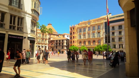 vibrant street scene in malaga's historic center with people exploring the charming plaza, surrounded by traditional spanish architecture and palm trees.
