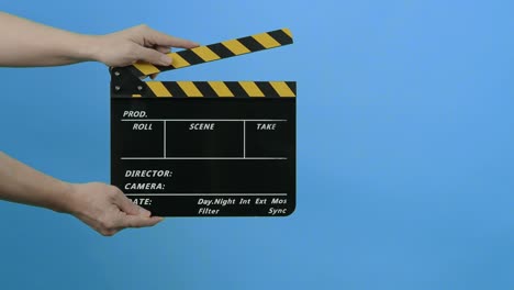 film slate or movie clapperboard with blue green screen background. film crew man hold and hit film slate in the frame. clapping film slate. video production chroma key background. video production.