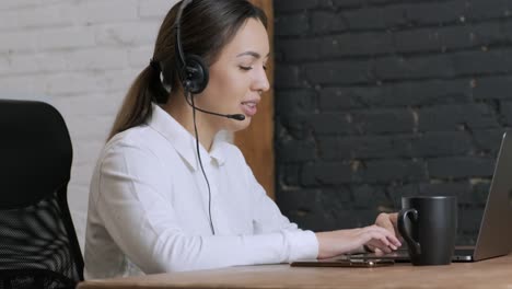 smiling woman call centre operator, customer support agent wears headset consults client online typing on laptop, talk in internet computer chat, helpline operator secretary make conference video call