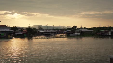 Blick-Auf-Den-Sonnenuntergang-über-Der-Schulter-Des-Hafens-Am-Wasser-In-Kanchanaburi,-Thailand