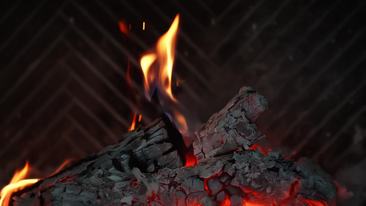 Slowmotion-vlammen krullen boven verkoolde blokken en gloeiende sintels in een open haard. Asachtige kolen en oranje licht creëren een gezellige wintersfeer voor verwarming of een filmische achtergrond