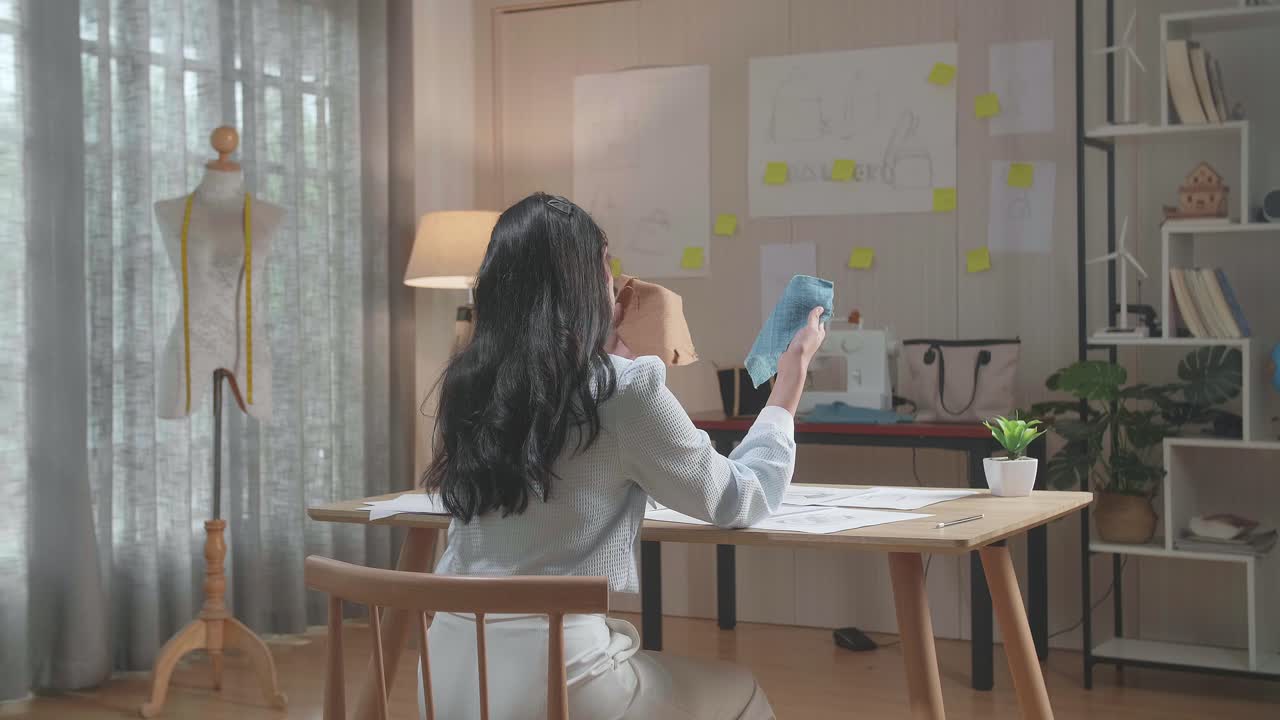 vista trasera de una mujer diseñadora de bolsas con enlace de diseño mirando la tela en las manos