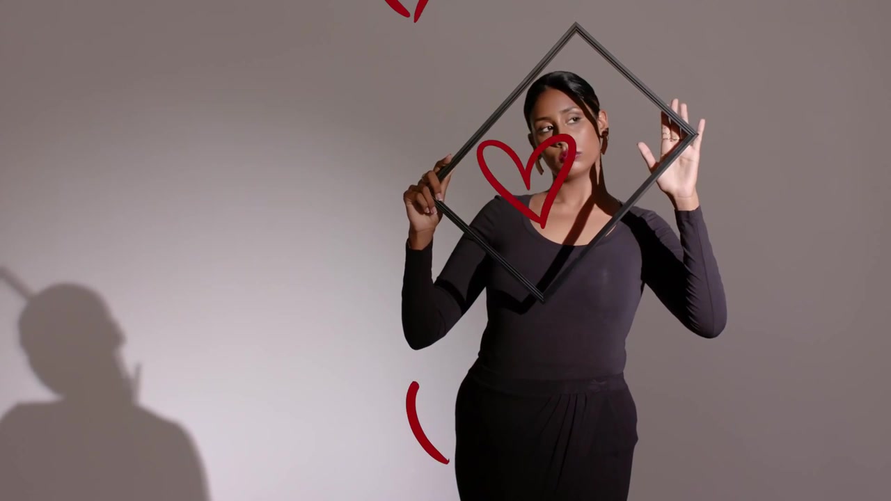 Video verticale: Cuori rossi che appaiono, modella che regola l'inquadratura per il servizio fotografico, indossando un abito nero.