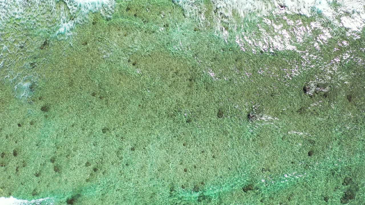 Waves foaming over calm shallow lagoon with pebbles on seabed, reflecting sunlight on shore of tropical island, Bermuda