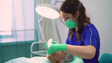 cosmetologist in gloves removes pimples from girl face