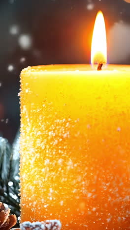 a candle is lit on a table with pine cones and other decorations. scene is warm and cozy, perfect for the holiday season