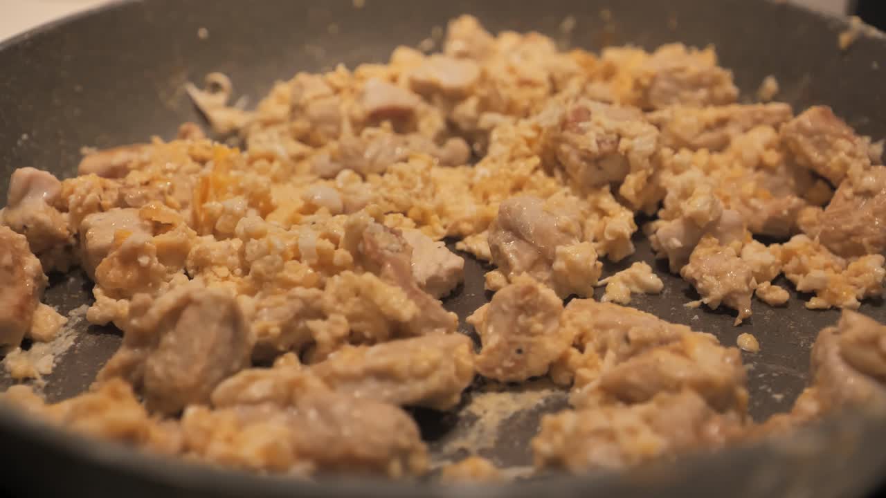 Extra close-up of woman stirring meat and scrambled eggs for final frying - 4K.