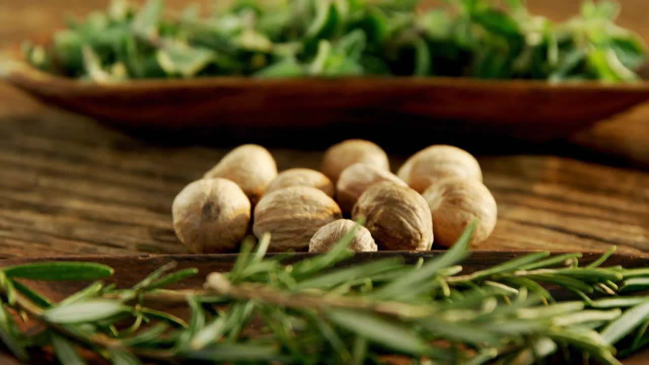 Nutmeg and rosemary on wooden surface with fresh herbs animation