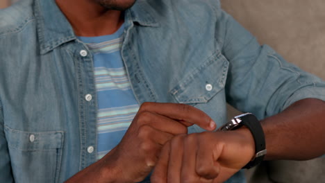 man using his smartwatch on couch