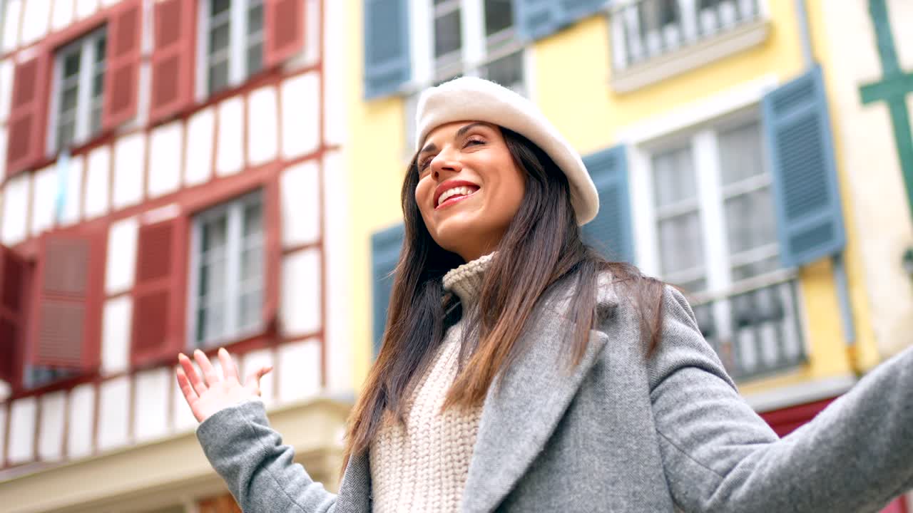 A woman in a beret stands in front of a building