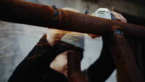 trabajador de la construcción cortando tubos viejos y oxidados con una molienda angular