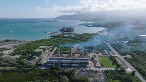 un disparo aéreo hacia atrás de humo se eleva en la subestación eléctrica en azua frente al mar caribe, república dominicana