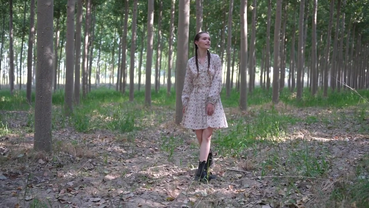 Una donna cammina tranquillamente lungo un sereno sentiero nel bosco, circondata da una vegetazione lussureggiante.