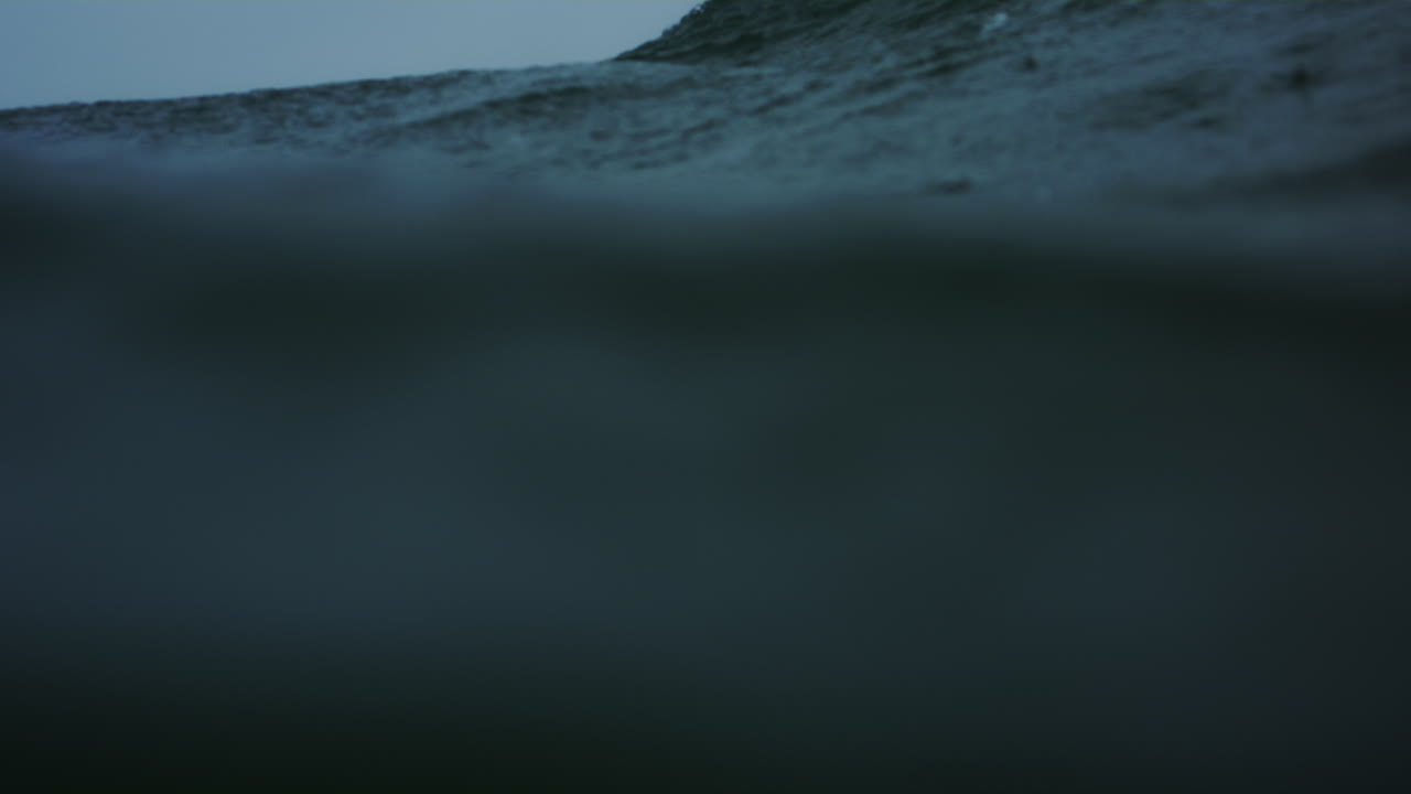 Frontal view of ocean water surface as rain drops fall and wave crashes exploding with power and whitewash