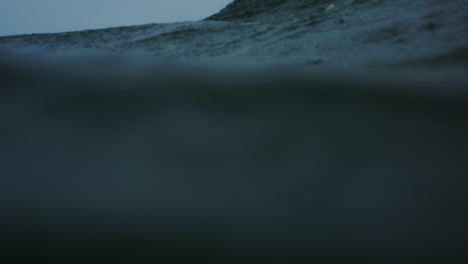 frontal view of ocean water surface as rain drops fall and wave crashes exploding with power and whitewash