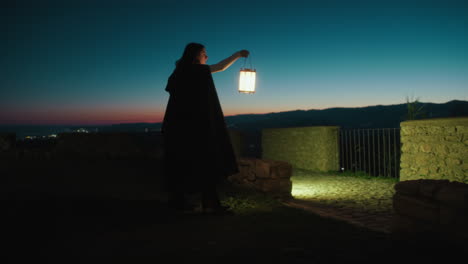 silhouette of mysterious woman with lantern walking on mountain at night