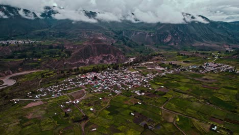 aerial drone panorama of maca district, with cloudy skies, revealing the colca river and the village of lari in the background