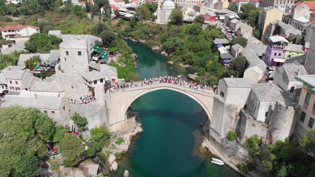 Havadan: Mostar'daki Stari Most üzerinde güneşli bir günde uçan drone. Yukarı doğru hareket.