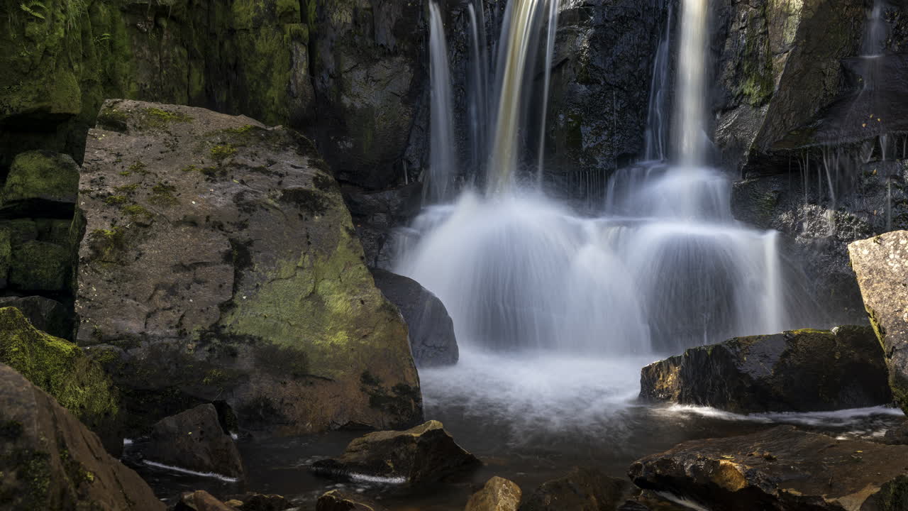 lapso de tiempo de la cascada local en el paisaje forestal rural de irlanda en un día soleado de verano