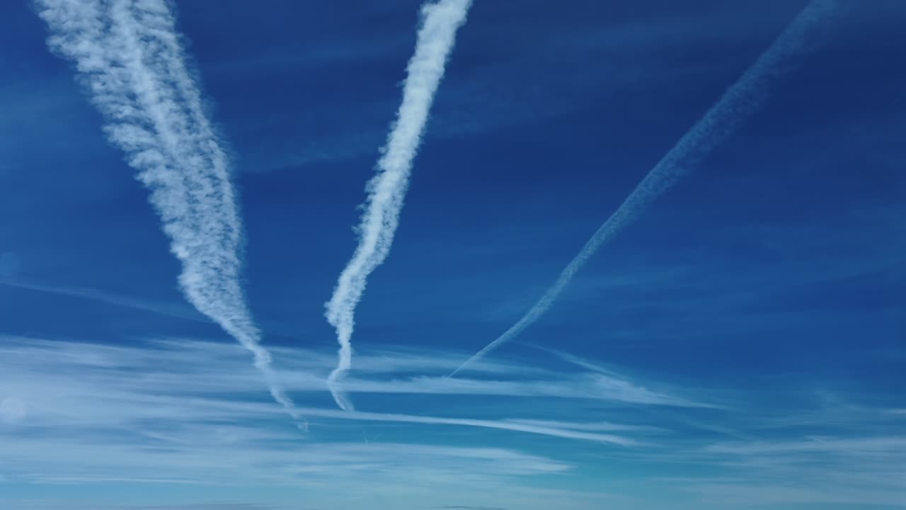 An aerial cockpit view of three parallel contrails in an intense blue color sky