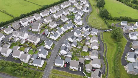 Drone-view-of-new-build-detached-and-semi-detached-homes-in-a-large-estate-in-the-UK-countryside,-surrounded-by-green-areas