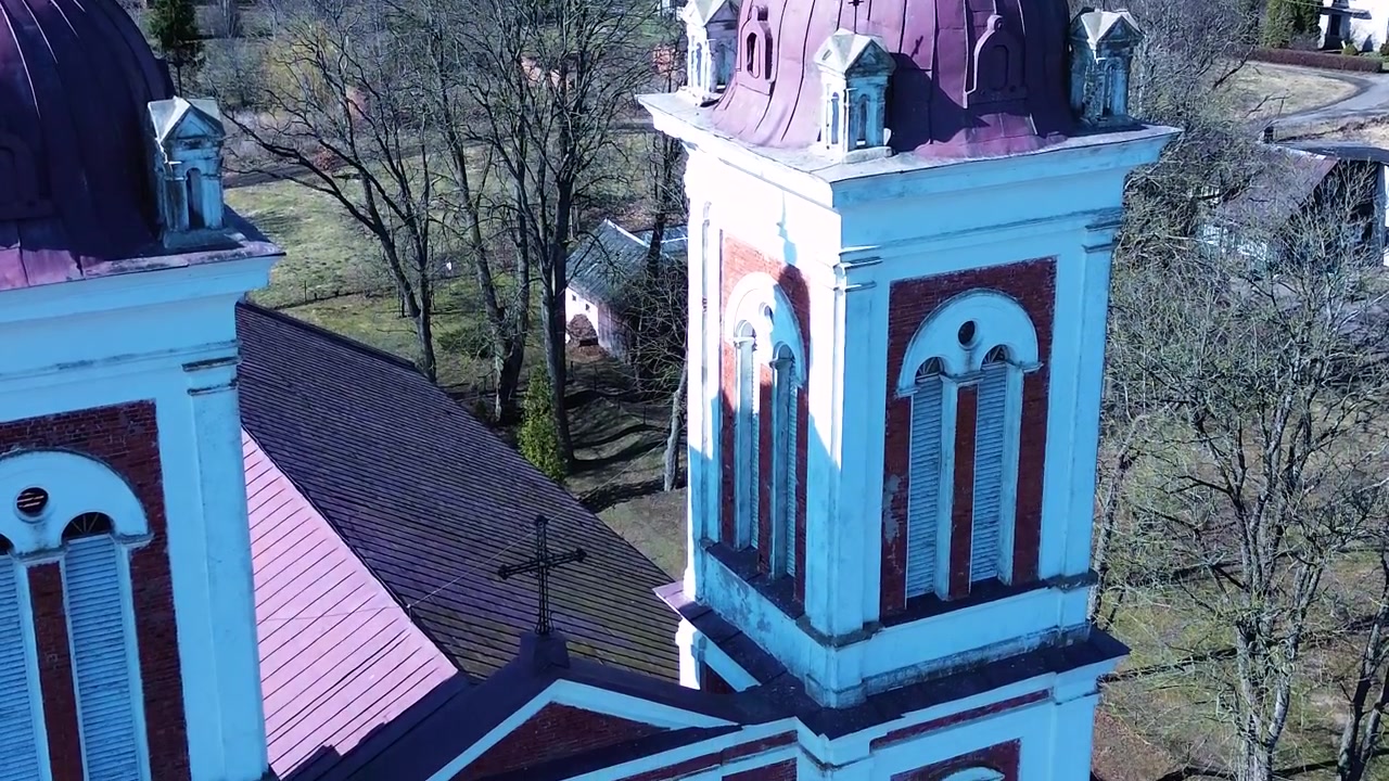 En kirke i en liten litauisk by med landlig landskap i bakgrunnen.