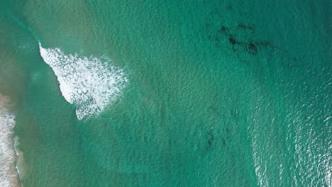 bird's eye view over turquoise ocean at belongil beach, byron bay, nsw, australia - drone shot