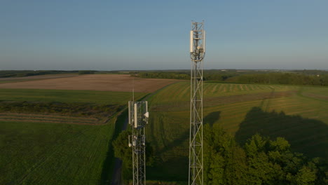 Dos-Torres-Celulares-En-Medio-De-Tierras-De-Cultivo-Durante-El-Amanecer,-Primer-Plano-Orbital-Aéreo