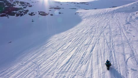 aerial view over snowy mountain landscape. snowmobile passing under. sunny weather. moving forward.