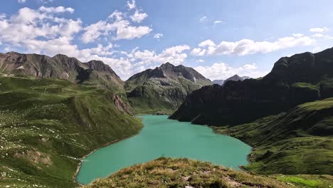 high viewpoint overlooking the turquoise waters of lago vannino in the lepontine alps, piedmont, italy, surrounded by green ridges and dramatic rocky peaks under a partly cloudy sky