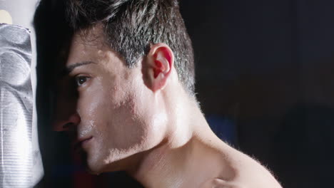 athletic man leaning his forehead to sandbag while having break