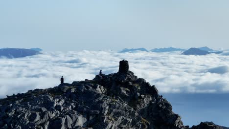 ascending on the rocky mountain peak with hikers in senja island, lonketinden, northern norway